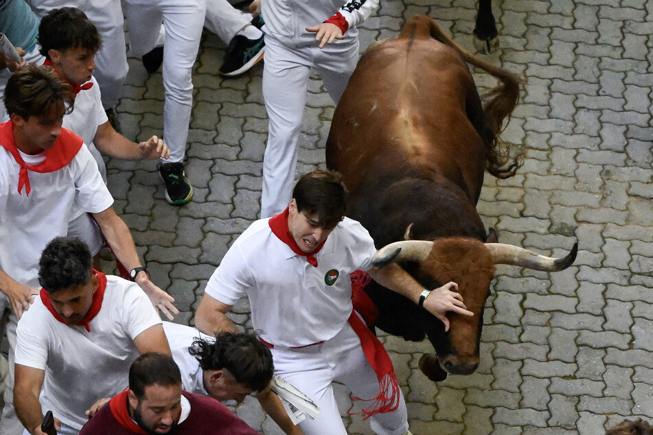 A runner barely evades a bull as participants run ahead of bulls from the Jandilla bull ranch during the eighth running of the bulls of the San Fermin festival in Pamplona, northern Spain, on July 14, 2026.
