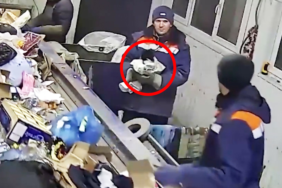 Stunned by the discovery of the cat, the garbage sorter stares into the video camera.