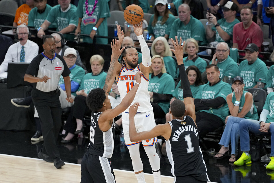 New York Knicks guard Jalen Brunson makes a jump shot over San Antonio Spurs guard Dylan Harper and forward Victor Wembanyama during the fourth quarter of game one of the 2026 NBA Finals at Frost Bank Center.