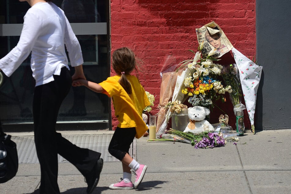 A young girl looks at a street shrine to six-year-old Etan Patz, who disappeared 33 years ago, set in front of the building where suspect Pedro Hernandez confessed to have strangled the boy in New York on May 29, 2012.