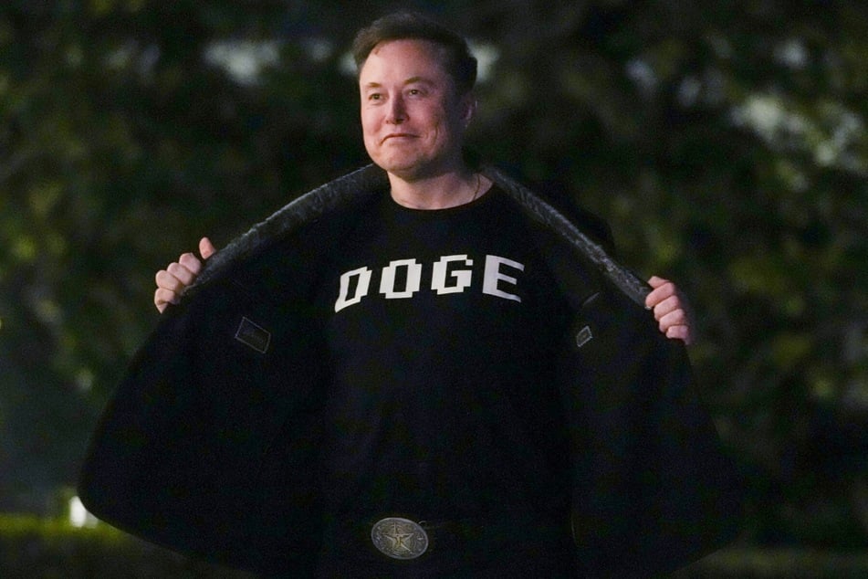 Elon Musk shows off a shirt that says "DOGE" as he walks on the South Lawn of the White House in Washington, DC, on March 9, 2025.