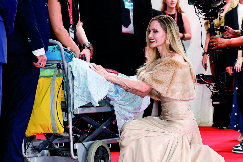 With a smile on her face, actor Angelina Jolie knelt down in front of her fan to greet him.