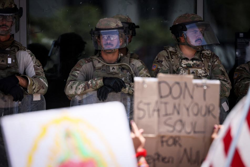 Demonstrators gather in front of the Federal Building in Los Angeles, California, guarded by a mix of US Marines and National Guard members, during the "No Kings" protest on July 4, 2025.