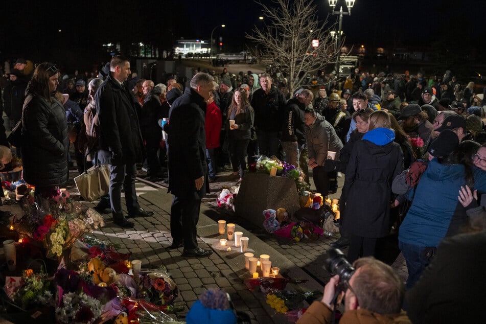 Canadian Prime Minister Mark Carney pays his respects amid a service for the victims of the February shooting in Tumbler Ridge. On Tuesday, a US man was arrested for allegedly helping the shooter.