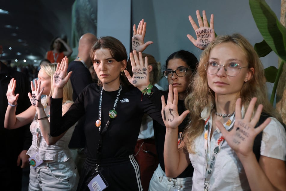 Activists show messages written on their hands as they take part in a protest while COP30 negotiators leave the meeting room on November 21, 2025.