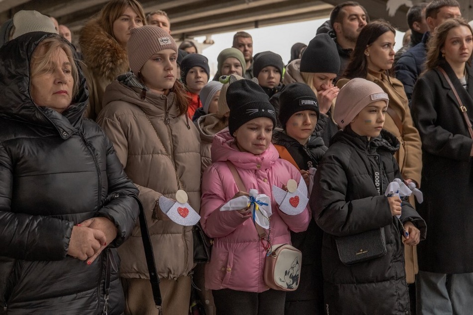 A young girl cries as local residents attend a memorial ceremony under a destroyed bridge in Irpin, northwest of Kyiv, on the second anniversary of Russia's invasion of Ukraine.