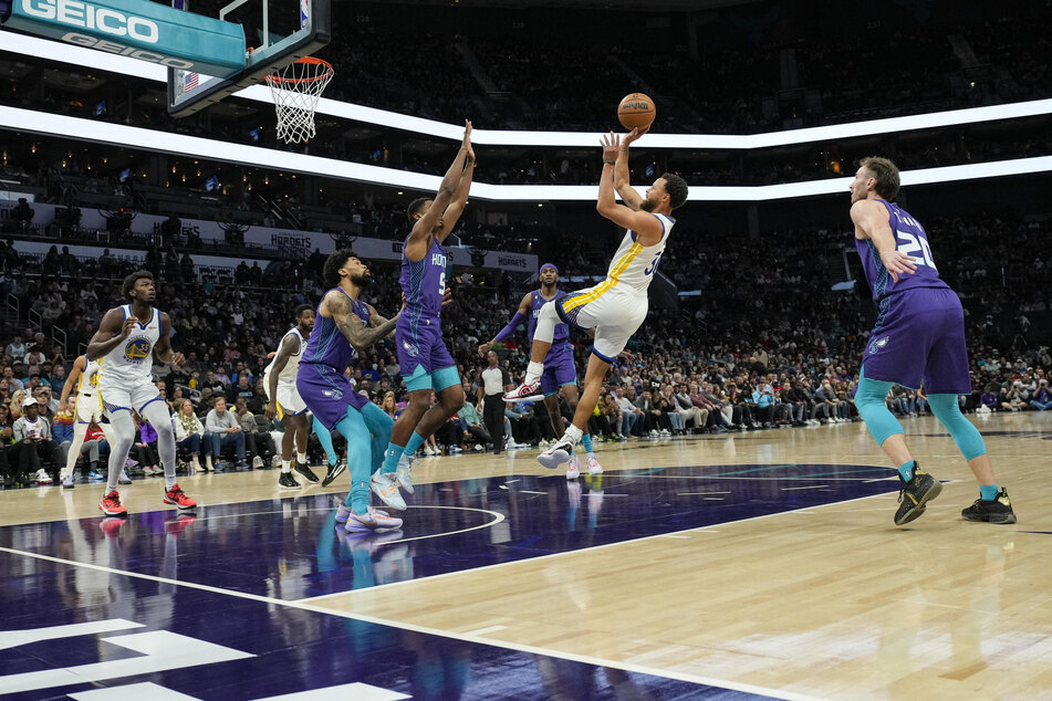 Golden State Warriors guard Stephen Curry takes an off-balance shot defended by Charlotte Hornets center Mark Williams during the first quarter at Spectrum Center.
