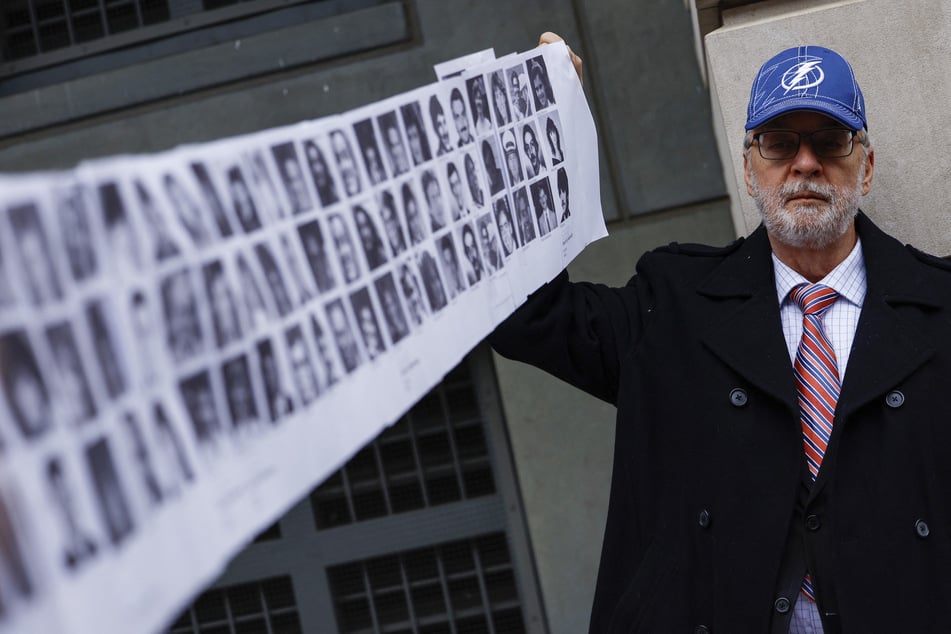 Paul Hudson, whose daughter Melina was one of the victims in the Pan Am Flight 103 Lockerbie bombing, holds up a banner of pictures of additional victims outside the federal court in Washington DC on December 12, 2022.