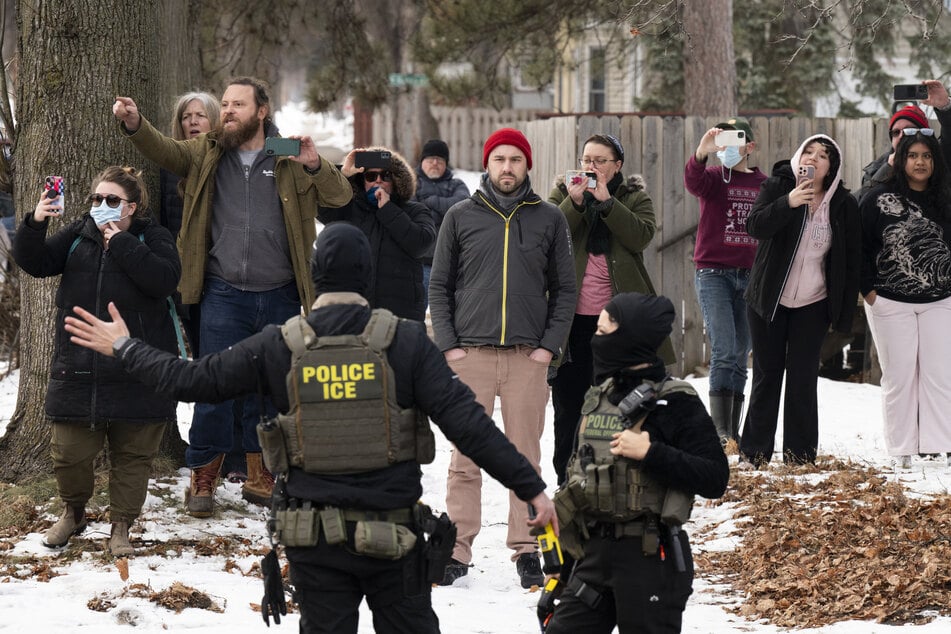 Observers film ICE agents as they hold a perimeter after one of their vehicles got a flat tire in Minneapolis, Minnesota, on February 5, 2026.