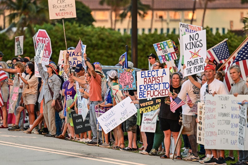 Protesters hold signs near President Donald Trump's Mar-a-Lago resort in Florida during the "No Kings" national day of protest on May 28, 2026. Another round of demonstrations is planned for October 17.