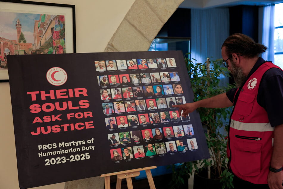 Eid Aziz, media director for the Red Crescent, points at pictures of Palestinian medics who were killed by the Israeli army, in Ramallah, in the Israeli-occupied West Bank, on August 19, 2026.