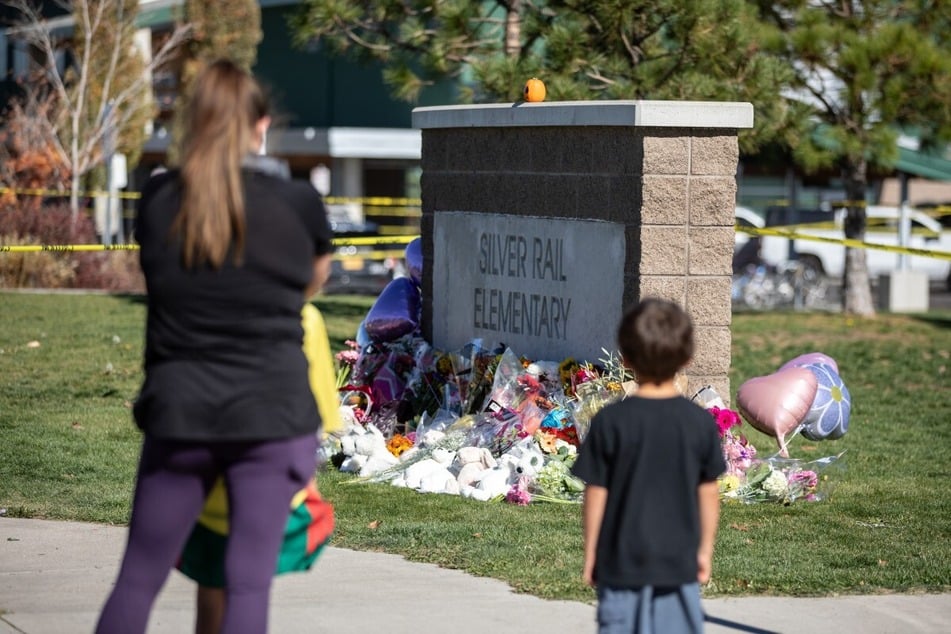 A woman and a child stand in front of a memorial at Silver Rail Elementary in Bend, Oregon. A shooting took place at the school on Thursday, killing three children and a teacher, and injuring two others.