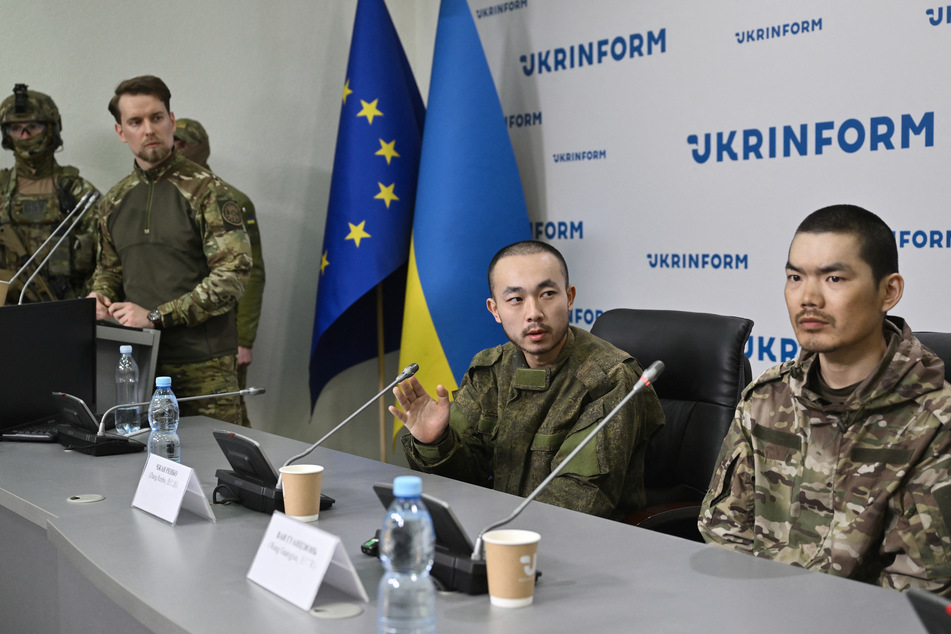 Chinese prisoners of war under armed guard Zhang Renbo (c.) and Wang Guangjun (r.) look on during a press conference in Kyiv on Monday, amid the Russian invasion of Ukraine.