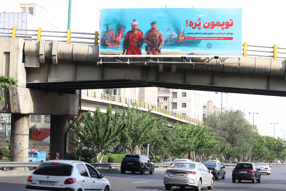 A large banner that reads in Persian, "Our cannons are full," referring to the Strait of Hormuz, is placed across a bridge that spans a highway in Tehran on May 12, 2026.