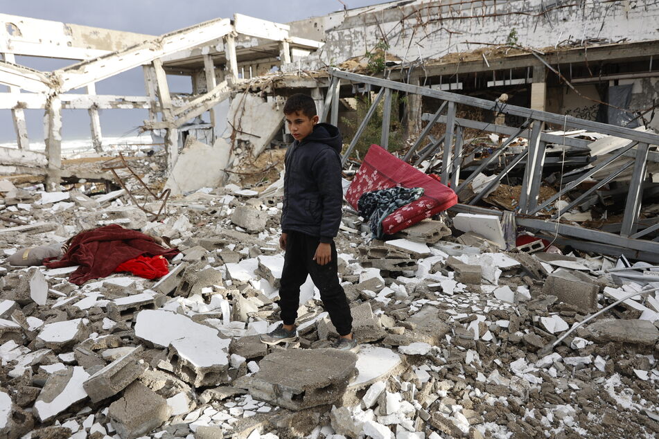 A Palestinian boy looks at the damage inside a destroyed building, parts of which collapsed on a windy winter day, in Gaza City on January 13, 2026.