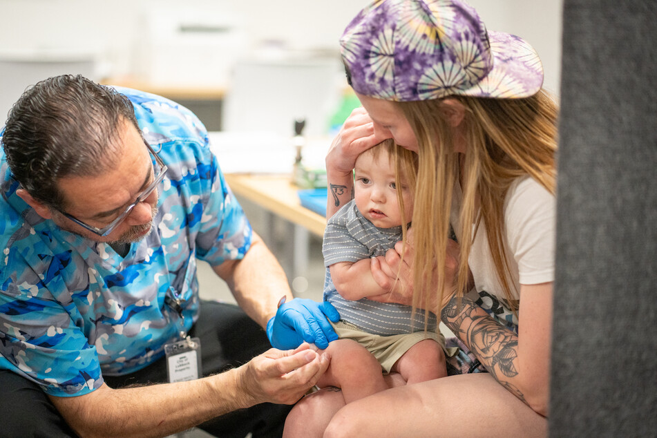 One-year-old River Jacobs is held by his mother, Caitlin Fuller, while he receives an MMR vaccine from Raynard Covarrubio, at a vaccine clinic put on by Lubbock Public Health Department on March 1, 2025 in Lubbock, Texas.