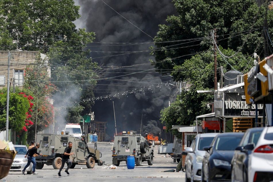 Palestinians run for cover amid an Israeli military operation in Jenin.