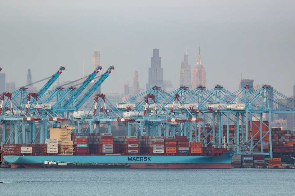 Cargo ships and shipping containers are seen at the Port Jersey Container Terminal, with the Manhattan skyline in the distance, on September 22, 2025.