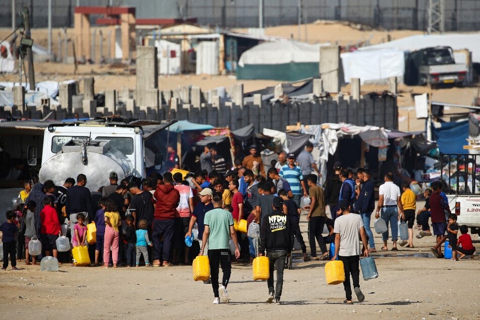 Displaced Palestinians line up to buy water from a truck next to their temporary camp in Rafah on May 17, 2024.