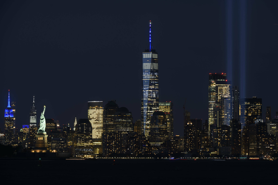 The Towers of Light illuminated memorial on the anniversary of 9/11 stands next to the newly erected Freedom Tower, in the destroyed World Trade Center's place, and across from the Statue of Liberty.