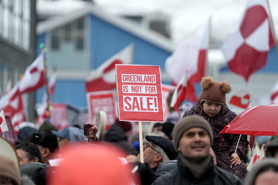 People wave Greenlandic flags as they take part in a massive demonstration in Nuuk to protest against Donald Trump's US takeover plans on January 17, 2026.