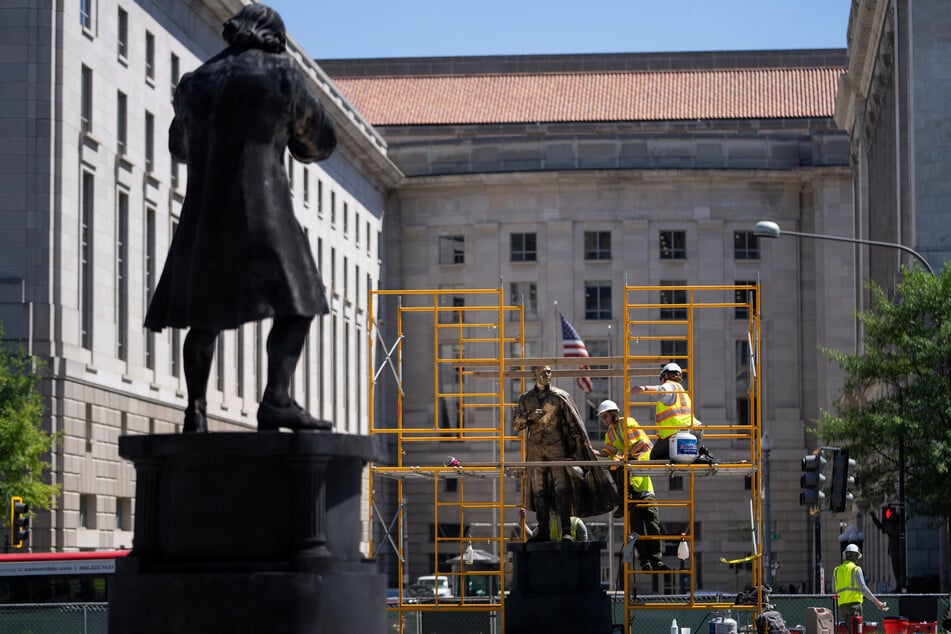 Workers add a gold finish to statues in Freedom Plaza near the White House, ahead of America 250, on June 3, 2026.