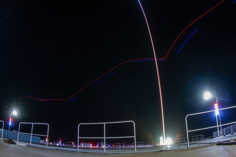 A long exposure image shows a track of a drone flying by as Long March 2F rocket carrying the Shenzhou-23 spacecraft blasts off to China's Tiangong space station on May 24, 2026.