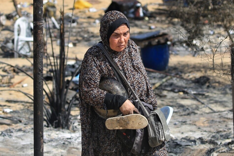 A Palestinian woman carries salvaged items following an Israeli raid in the al-Mawasi area in Rafah in the southern Gaza Strip.