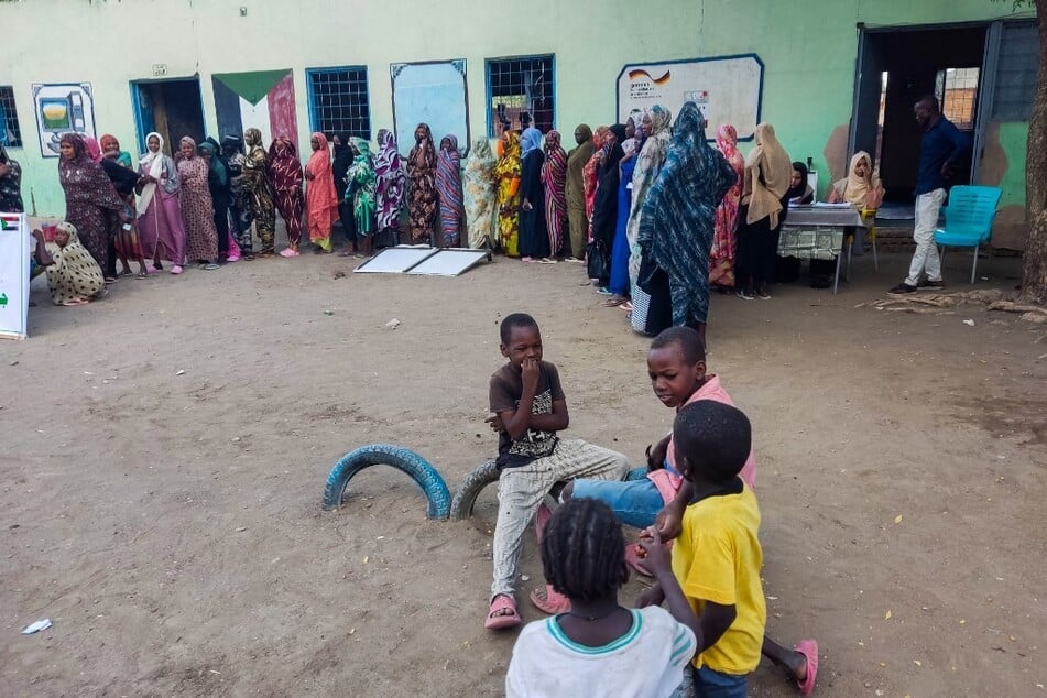 Internally displaced women wait in a queue to collect aid at a camp in Gadaref, Sudan.