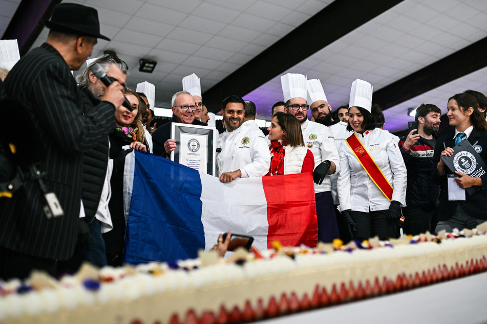 Pastry chef and owner of pastry shop La Maison Heloise, Youssef El Gatou (C/R) poses holding his Guinness World record certificate for the world's largest strawberry cake, 399 feet, eight inches long, during a Guinness World Record event in Paris on Wednesday.