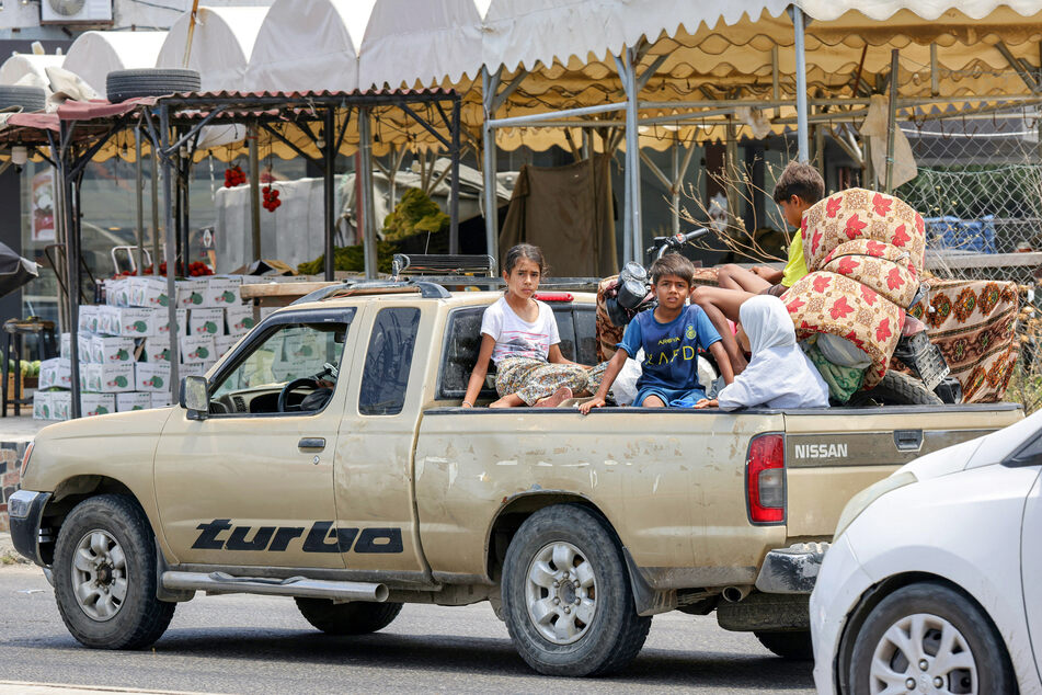 Children sit in the bed of a pickup truck waiting in traffic, as people flee from Tyre in southern Lebanon to seek refuge in more northerly Sidon, on June 9, 2026.