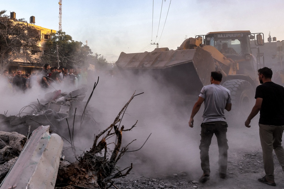 An excavator clears rubble as people search for survivors and the bodies of victims in the aftermath of Israeli bombardment in Rafah in the southern Gaza Strip on November 6, 2023.