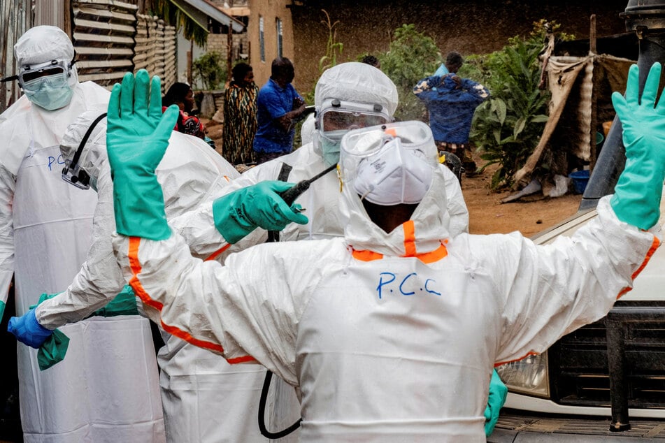 Members of the Civil Protection team, which works to help mitigate the spread of the Ebola virus, disinfect after handling the body of an unidentified man who died of the virus, in Bunia, Ituri province, Democratic Republic of Congo.
