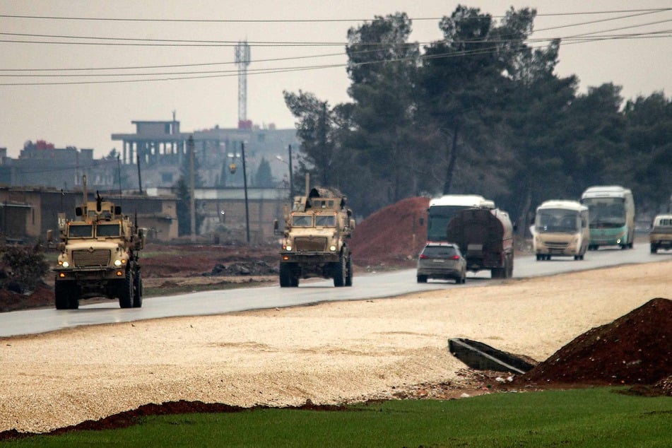 US military vehicles move along a road in a convoy transporting Islamic State group detainees being transferred to Iraq from Syria, on the outskirts of Qahtaniyah in Syria's northeastern Hasakah province on February 7, 2026.