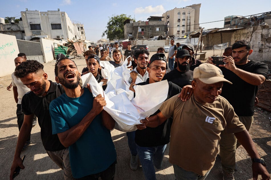 Mourners carry the body of one of three Palestinians during their funeral at Al-Shifa Hospital in Gaza City on October 25, 2026, after they were killed in an Israeli strike on the building.