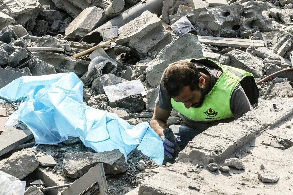 A first responder uses a flash light as he searches for victims amidst the rubble in the aftermath of an Israeli airstrike that targeted a house in the southern Lebanese village of Ansar on August 15, 2026.