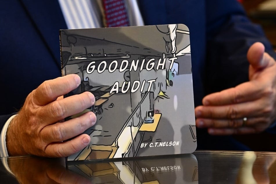 Bill Gates holds a copy of the Goodnight Audit children’s book by Trevor Nelson.