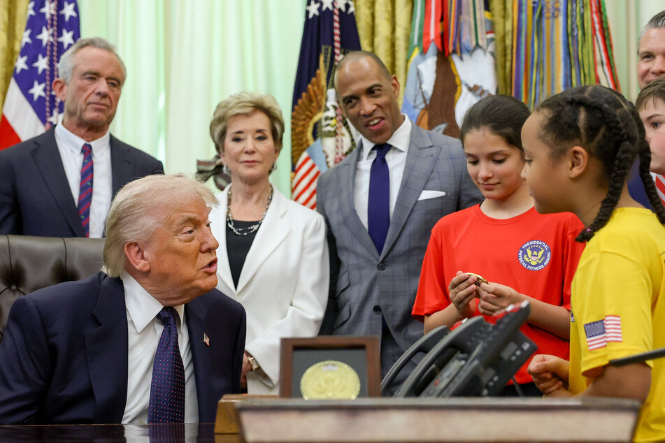 President Trump (l.) hosted several young athletes in the Oval Office to sign the proclamation.