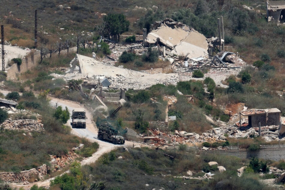 Israeli military vehicles drive past houses destroyed in Israeli strikes in a southern Lebanese village on July 1, 2026.