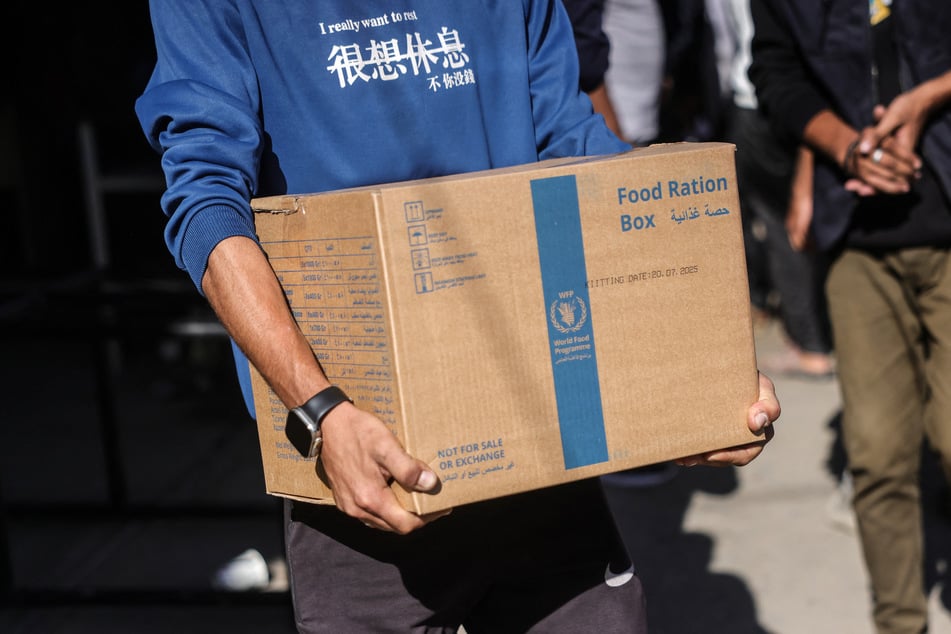 A Palestinian man carries a food ration box provided by the World Food Programme at a distribution center in the village of Al-Zawayda, in the center of the Gaza Strip, on October 27, 2025. The WFP has said it must reduce food aid to Gaza amid severe funding cuts.