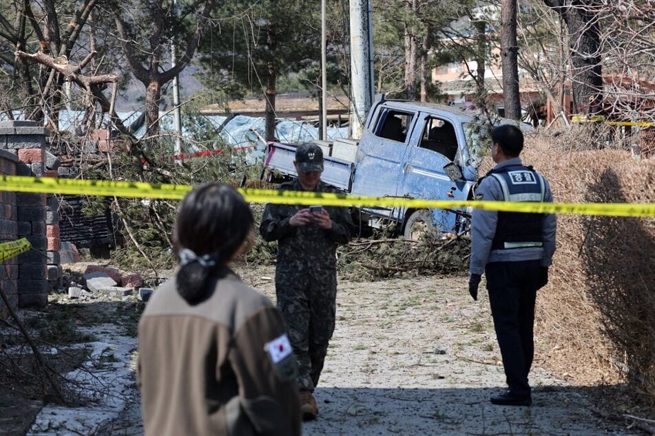 South Korean soldiers and a policeman stand next to a damaged vehicle after a bomb accident at a village in Pocheon on March 6, 2025.