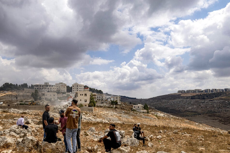 Palestinian men watch as an Israeli army excavator demolishes a Palestinian building on the outskirts of Nablus in the Israeli-occupied West Bank on August 31, 2026.