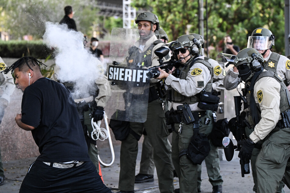 Los Angeles County Sheriff's Department deputies fire a nonlethal weapon toward a man after he threw a can at them following a protest against federal immigration operations near Los Angeles City Hall in Los Angeles on Wednesday.