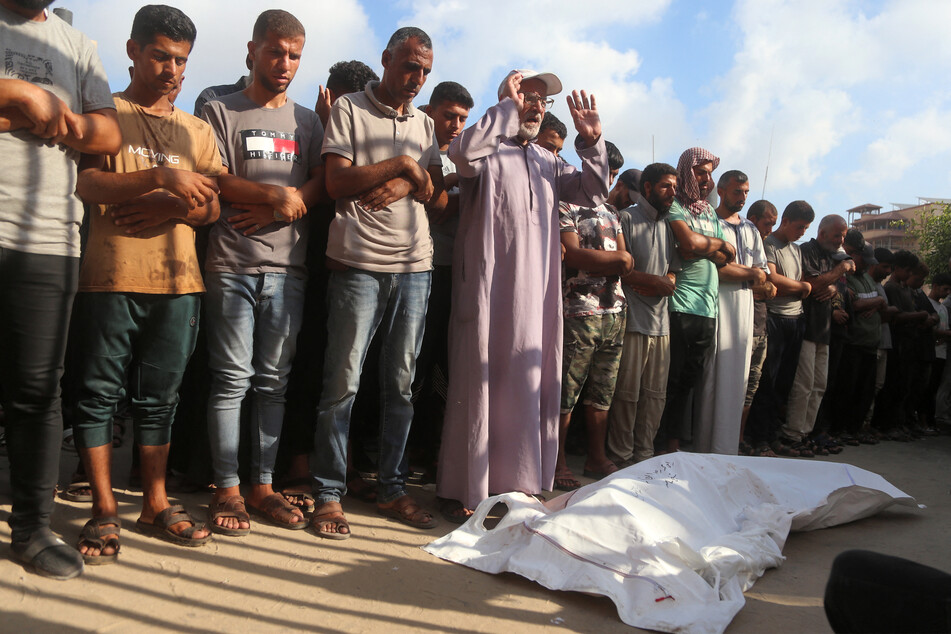 Mourners pray by the bodies of victims who were killed the previous day by Israeli bombardment as they lie outside during the funeral at Nasser Medical Complex in Khan Younis on July 20, 2025.