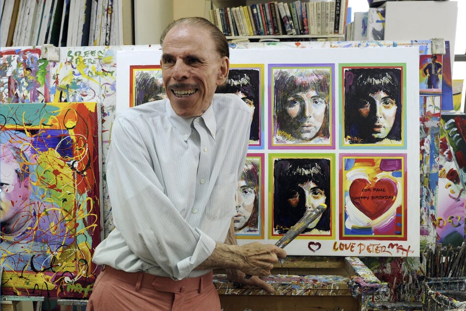 Peter Max poses in his New York studio on June 18, 2012, with seven portraits he created of Paul McCartney to commemorate the musician’s 70th birthday.