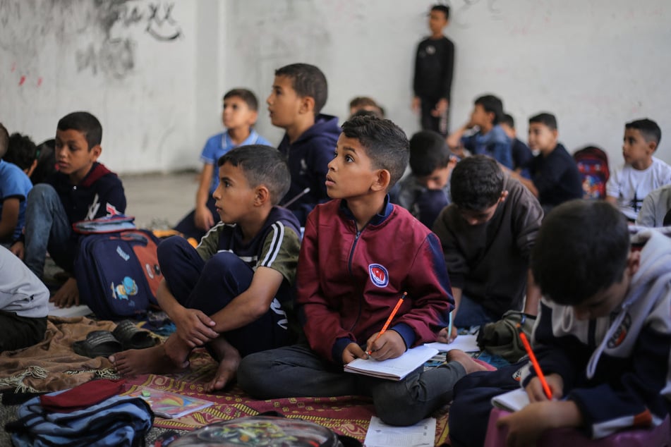 Palestinian children listen to their teacher at a school in the Nuseirat refugee camp, in the central Gaza Strip, on October 26, 2025.