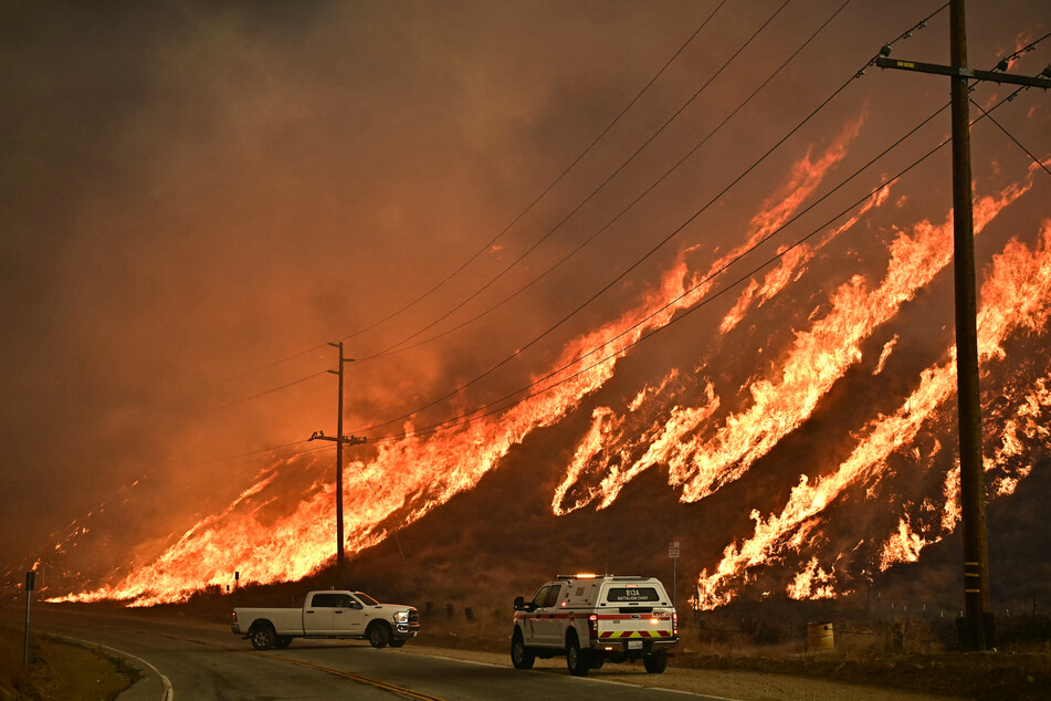 Emergency vehicles are on the side of the road as flames from the Hughes Fire race up the hill in Castaic, a northwestern neighborhood of Los Angeles, California, on January 22, 2025.