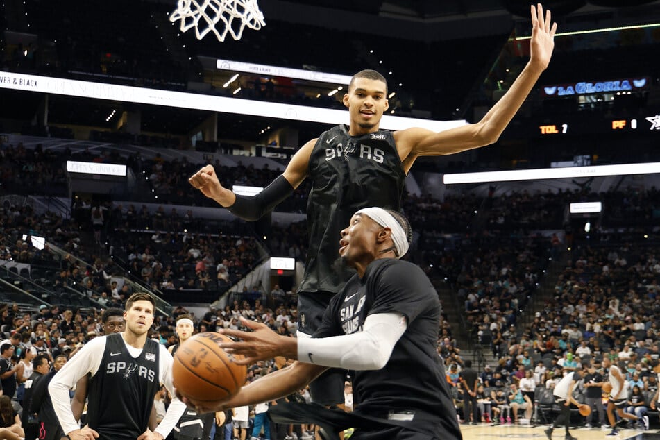 Victor Wembanyama looks to block Devonte Graham during a San Antonio Spurs training game watched by thousands of fans.