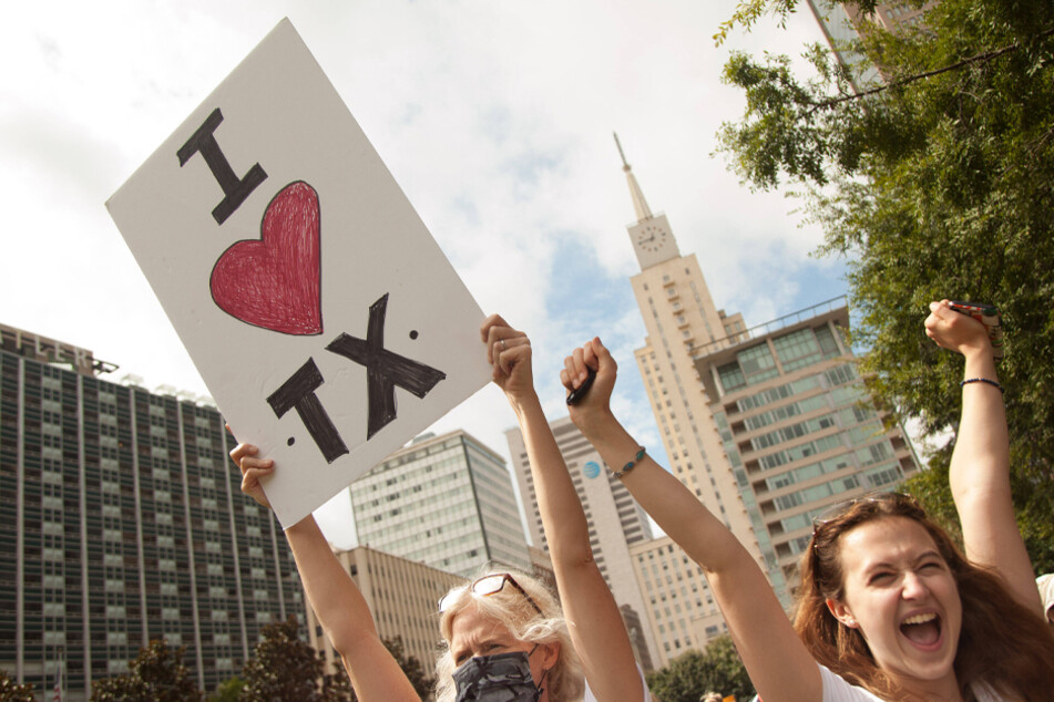 People hold up signs at the Dallas Reproductive Liberation March in Dallas, Texas on October 2.