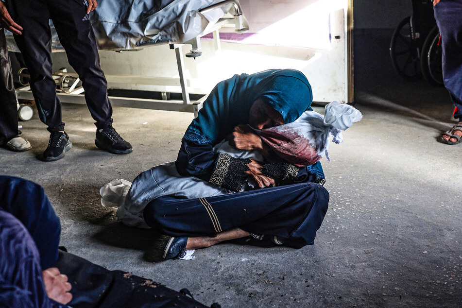A Palestinian woman holds the shrouded body of child killed in Israeli bombardment, at a health clinic in the area of Tel al-Sultan in Rafah in the southern Gaza Strip on Sunday.